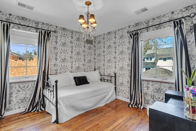 bedroom with wallpapered walls, a chandelier, and wood finished floors