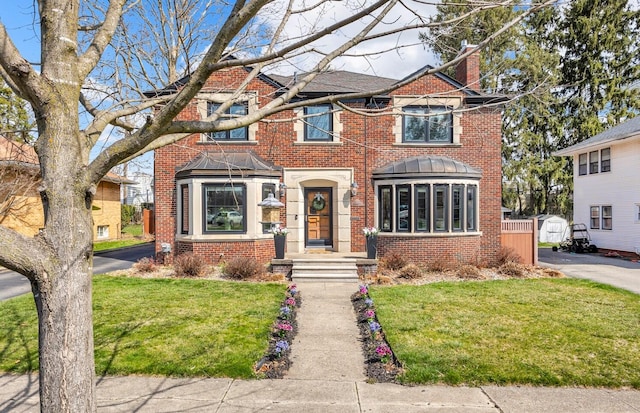 townhome / multi-family property featuring a front yard, a chimney, and brick siding