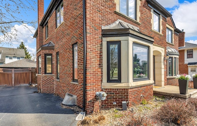 view of property exterior featuring fence and brick siding