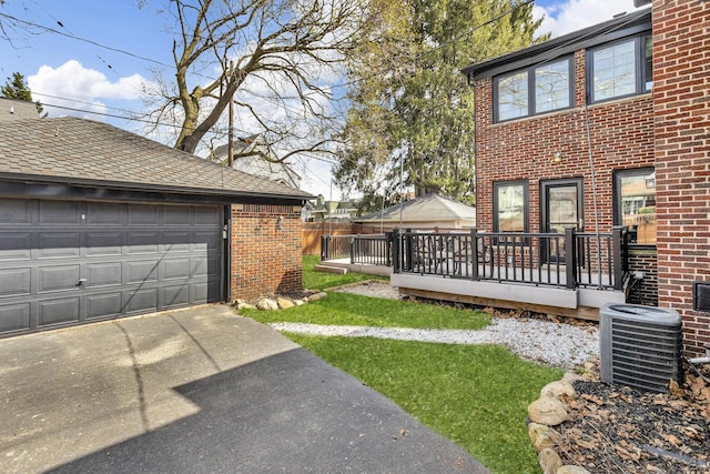 view of yard featuring an outdoor structure, a deck, a detached garage, and central air condition unit