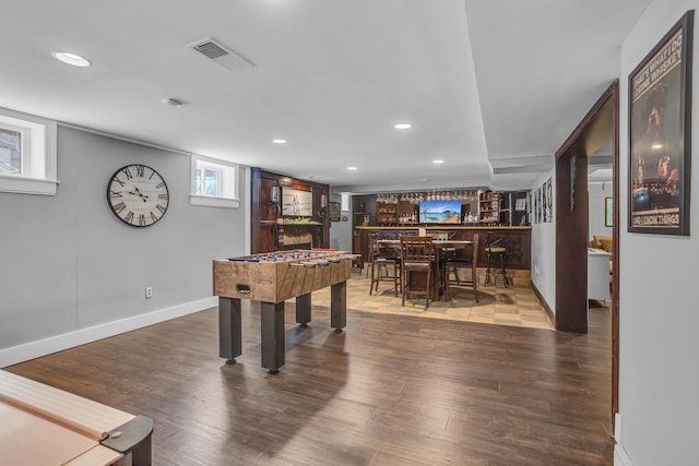 rec room featuring wood finished floors, bar area, recessed lighting, and visible vents