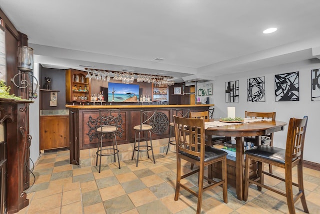 dining room featuring recessed lighting, a dry bar, stone finish flooring, and visible vents