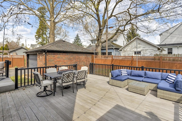 deck with an outdoor hangout area, outdoor dining area, an outbuilding, and a fenced backyard