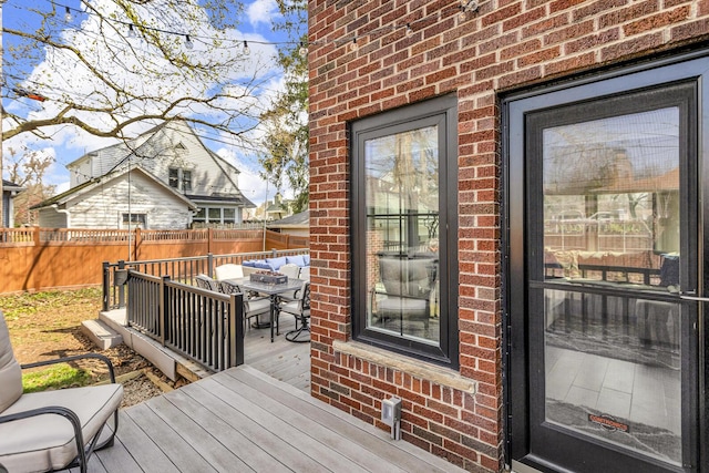 wooden deck with outdoor dining area and a fenced backyard