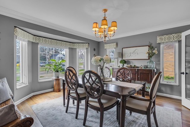 dining space featuring ornamental molding, light wood-type flooring, a chandelier, and baseboards