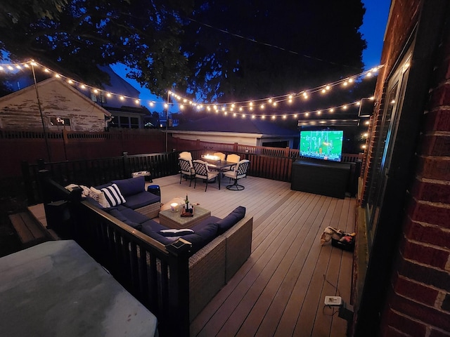 deck at night featuring an outdoor hangout area and fence