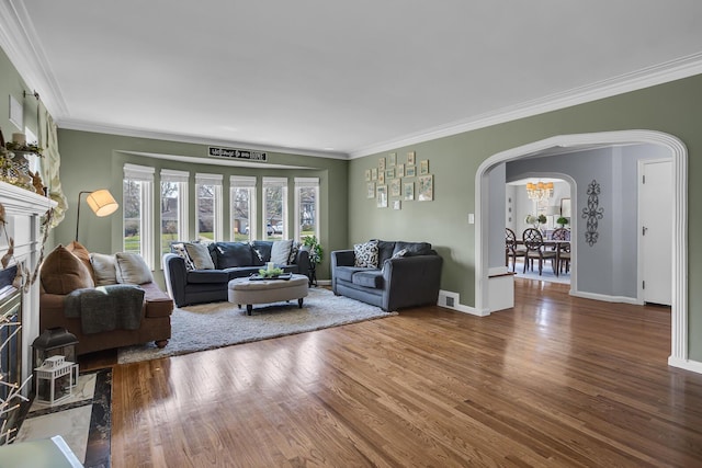living area with visible vents, ornamental molding, wood finished floors, and arched walkways