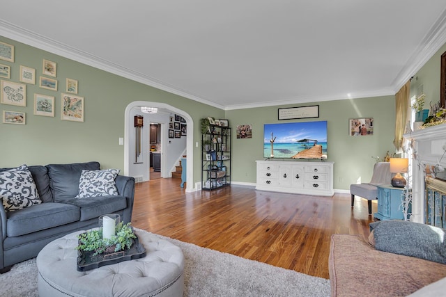 living area featuring wood finished floors, ornamental molding, stairs, and arched walkways