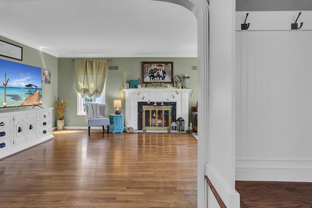 living room with visible vents, ornamental molding, a high end fireplace, and wood finished floors