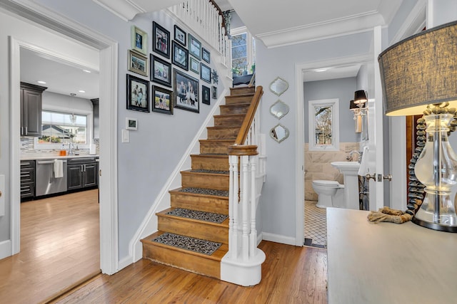 stairs with a wealth of natural light, wood finished floors, and ornamental molding