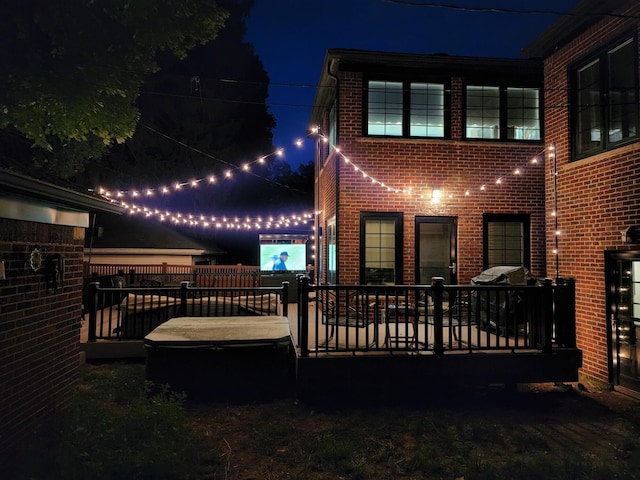 back of house at twilight featuring brick siding
