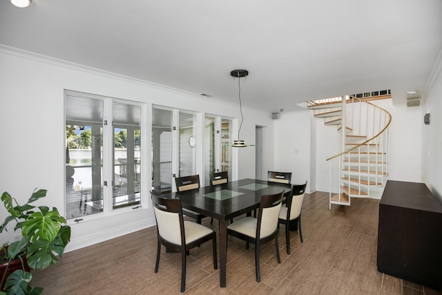 dining area featuring wood finished floors, a water view, baseboards, stairway, and crown molding