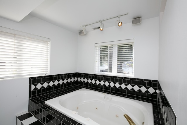 full bathroom with a tub with jets, track lighting, and visible vents