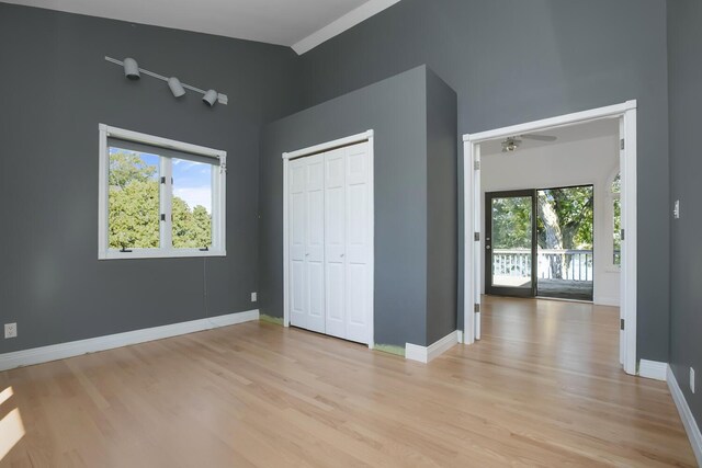 unfurnished bedroom with multiple windows, baseboards, and light wood-type flooring