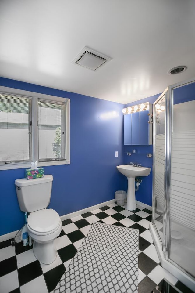bathroom featuring tile patterned floors, toilet, and a stall shower