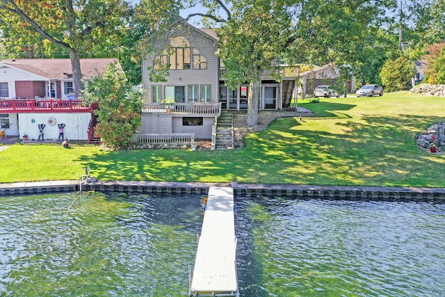 rear view of property with a deck with water view, a yard, and stairs