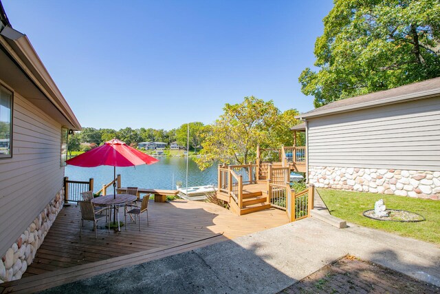 deck with outdoor dining area and a water view