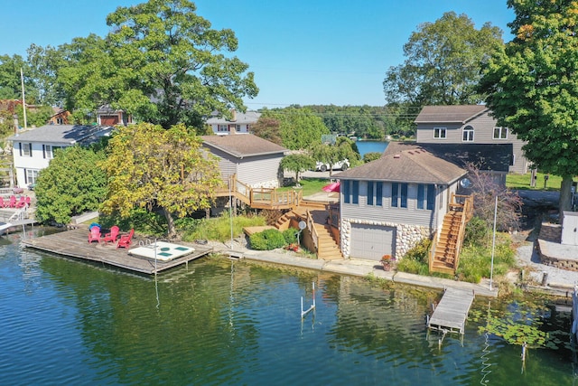 exterior space featuring a deck with water view, stairs, and a shingled roof