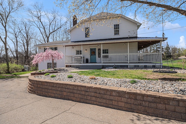 view of front facade with covered porch and a chimney