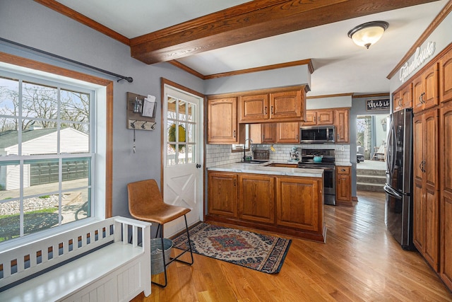 kitchen featuring brown cabinetry, appliances with stainless steel finishes, and plenty of natural light
