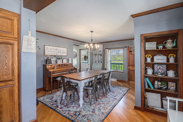 dining area featuring light wood-style floors, visible vents, baseboards, ornamental molding, and a notable chandelier