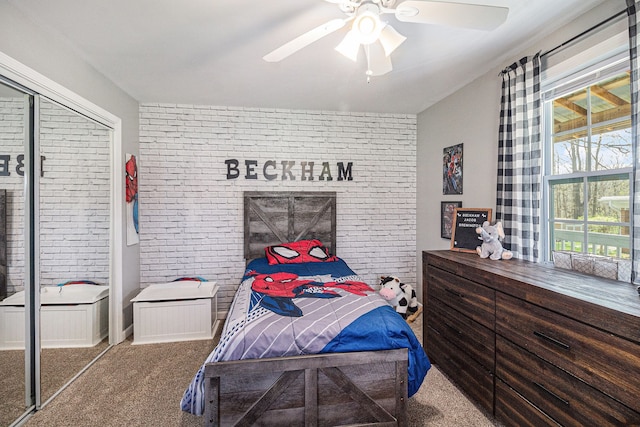 bedroom featuring a ceiling fan, carpet flooring, a closet, and brick wall