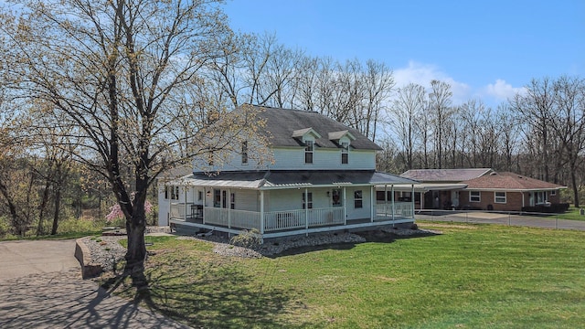 country-style home featuring metal roof, a front lawn, driveway, and covered porch