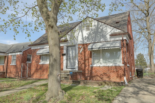 view of front of home with a shingled roof and brick siding