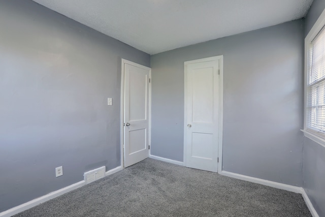 spare room with plenty of natural light, visible vents, carpet, and baseboards
