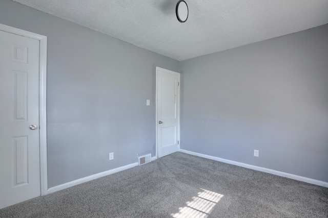 carpeted empty room featuring baseboards, visible vents, and a textured ceiling