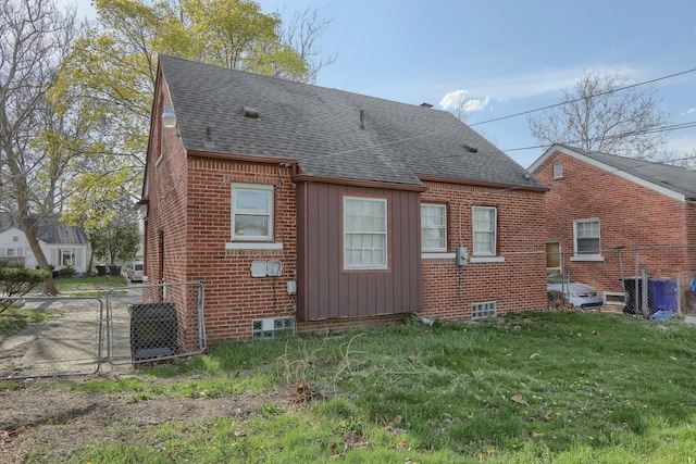 rear view of house featuring a gate, a shingled roof, fence, a yard, and brick siding