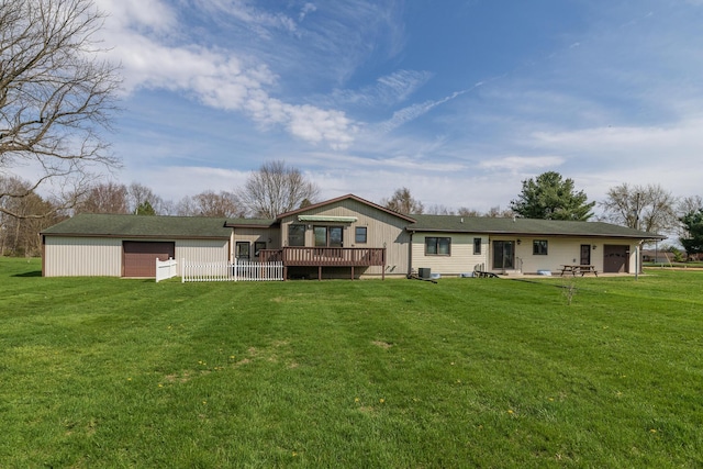 back of house with a lawn, a detached garage, and a wooden deck