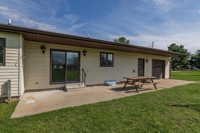 rear view of house featuring a garage, entry steps, a yard, and a patio area