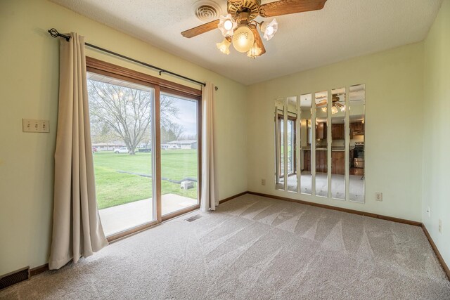 carpeted spare room with a ceiling fan, visible vents, a textured ceiling, and baseboards