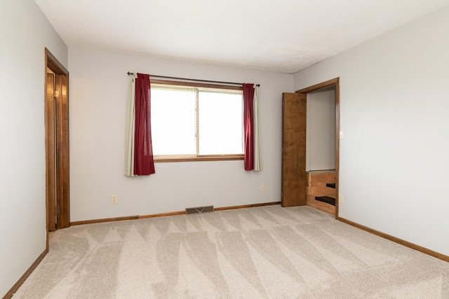 empty room featuring visible vents, light carpet, and baseboards