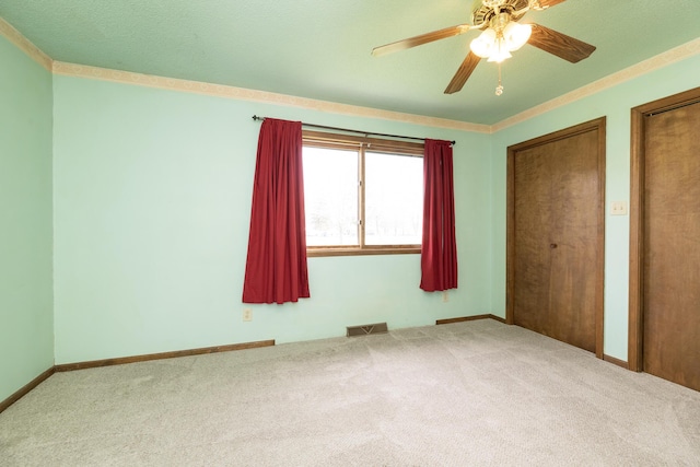 unfurnished bedroom with visible vents, ceiling fan, multiple closets, and carpet floors