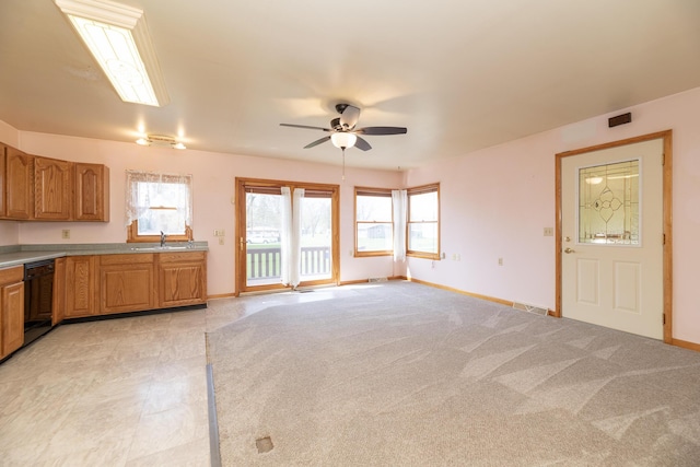 kitchen with a sink, ceiling fan, light countertops, baseboards, and black dishwasher