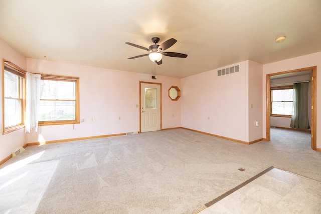 spare room with a ceiling fan, visible vents, light carpet, and baseboards
