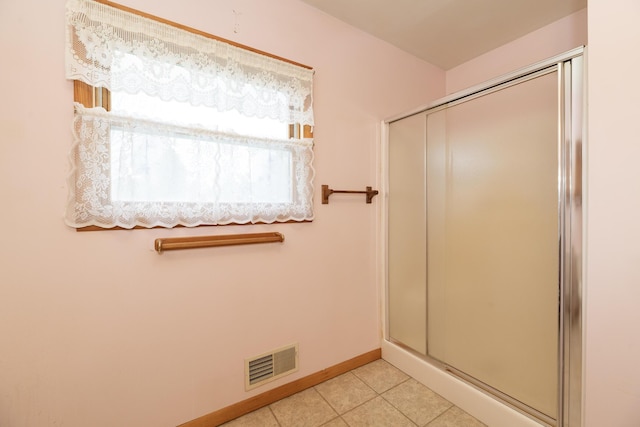 bathroom with a shower with shower door, tile patterned flooring, visible vents, and baseboards