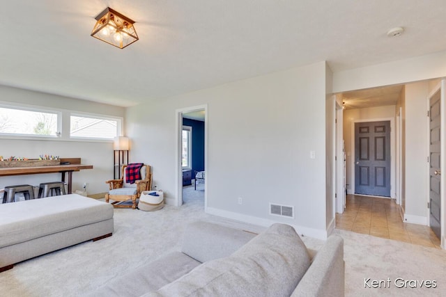 living room with visible vents, baseboards, and light carpet
