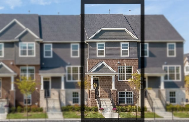 townhome / multi-family property featuring brick siding and a fenced front yard