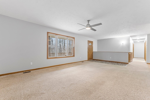 spare room featuring ceiling fan, light carpet, visible vents, and baseboards