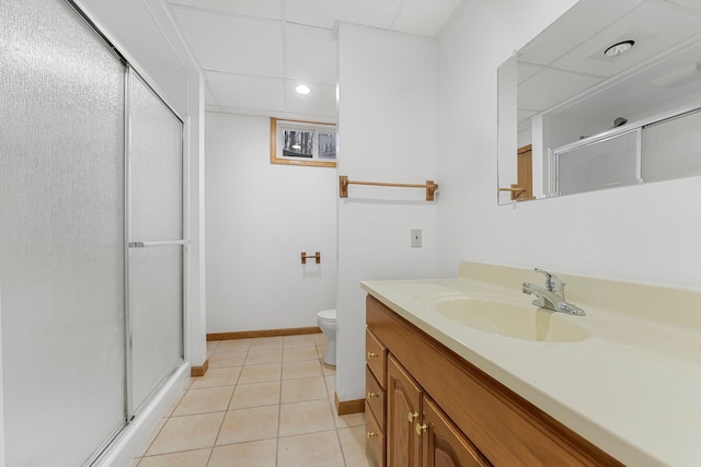 full bath featuring a shower stall, vanity, toilet, baseboards, and tile patterned flooring