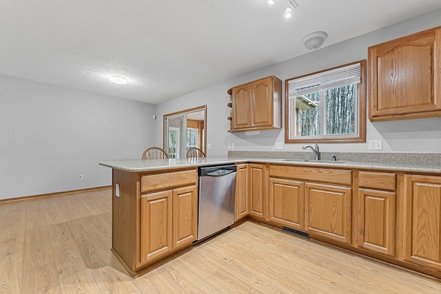 kitchen with a sink, light wood-style flooring, a peninsula, light countertops, and dishwasher