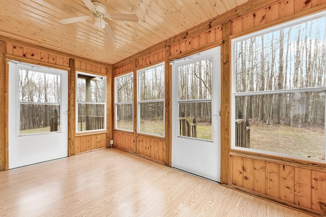 unfurnished sunroom featuring wooden walls, ceiling fan, and a healthy amount of sunlight