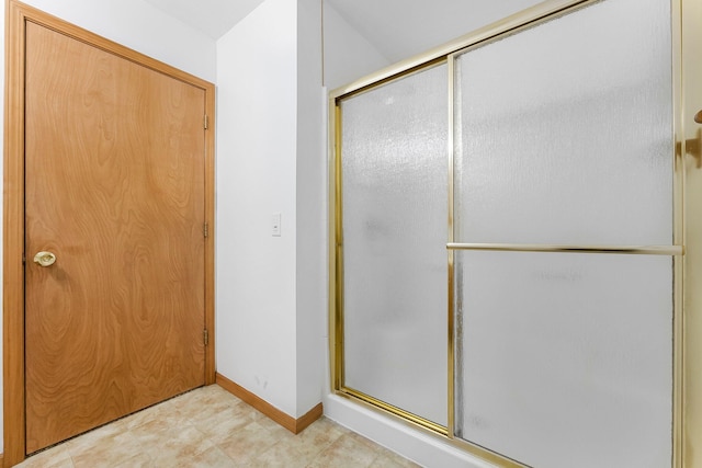 full bath with baseboards and a shower with shower door
