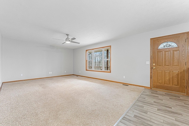 foyer featuring baseboards, visible vents, ceiling fan, and light wood finished floors
