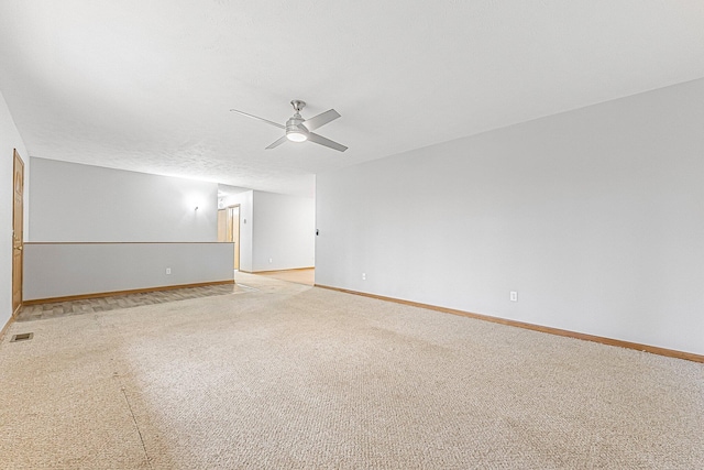spare room featuring a ceiling fan, visible vents, light colored carpet, and baseboards