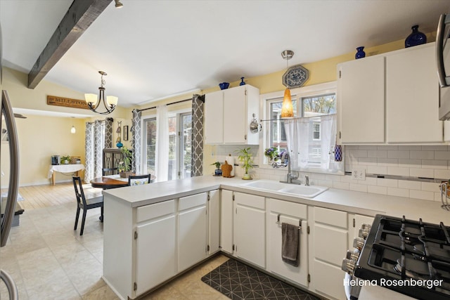 1456 54th St SE, Grand Rapids, MI 49508 - kitchen with a peninsula, light countertops, a sink, backsplash, and hanging light fixtures