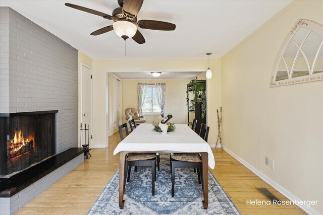 1456 54th St SE, Grand Rapids, MI 49508 - dining space with visible vents, a fireplace, baseboards, ceiling fan, and light wood finished floors